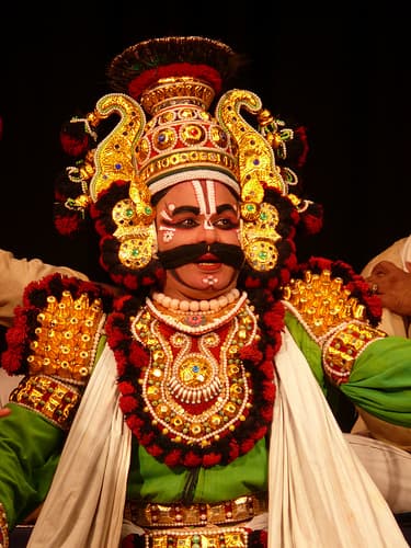 Yakshagana artist in traditional costume, painted face and ornate golden headdress